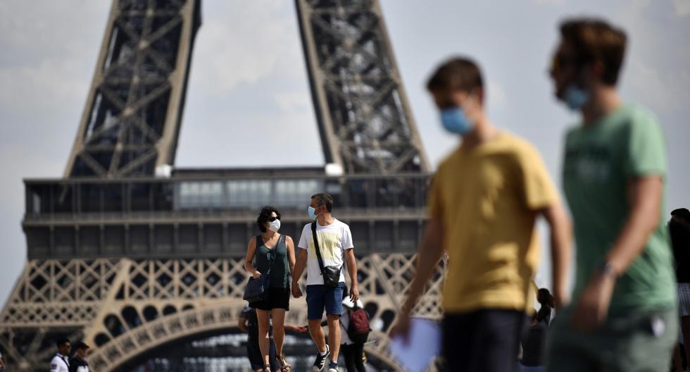 Personas con mascarillas caminan frente a la Torre Eiffel, como parte de las medidas para contener la propagación del coronavirus en París (Francia). (EFE/EPA/Julien de Rosa).