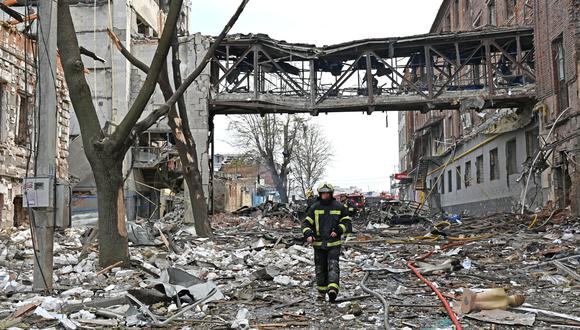 Un rescatista pasa frente a edificios destruidos tras el bombardeo, matando a dos personas e hiriendo a otras dieciocho, según la oficina del fiscal de la región de Kharkiv, en la ciudad ucraniana de Járkov el 16 de abril de 2022. (Foto por SERGEY BOBOK / AFP)