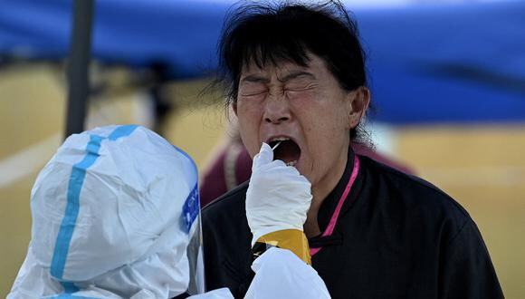 Un trabajador de la salud toma una muestra de hisopo de una mujer para analizarla por el coronavirus Covid-19 en un sitio de recolección de hisopos en Beijing el 23 de junio de 2022. (Foto de Noel Celis / AFP)