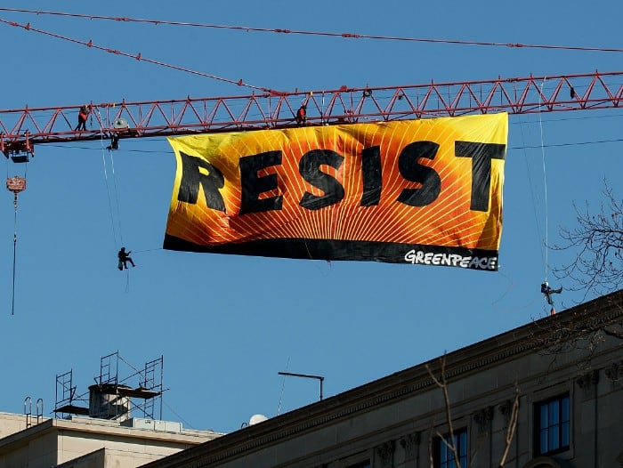Activistas de Greenpeace se montaron en una grúa y colgaron una banderola con la palabra "Resiste".