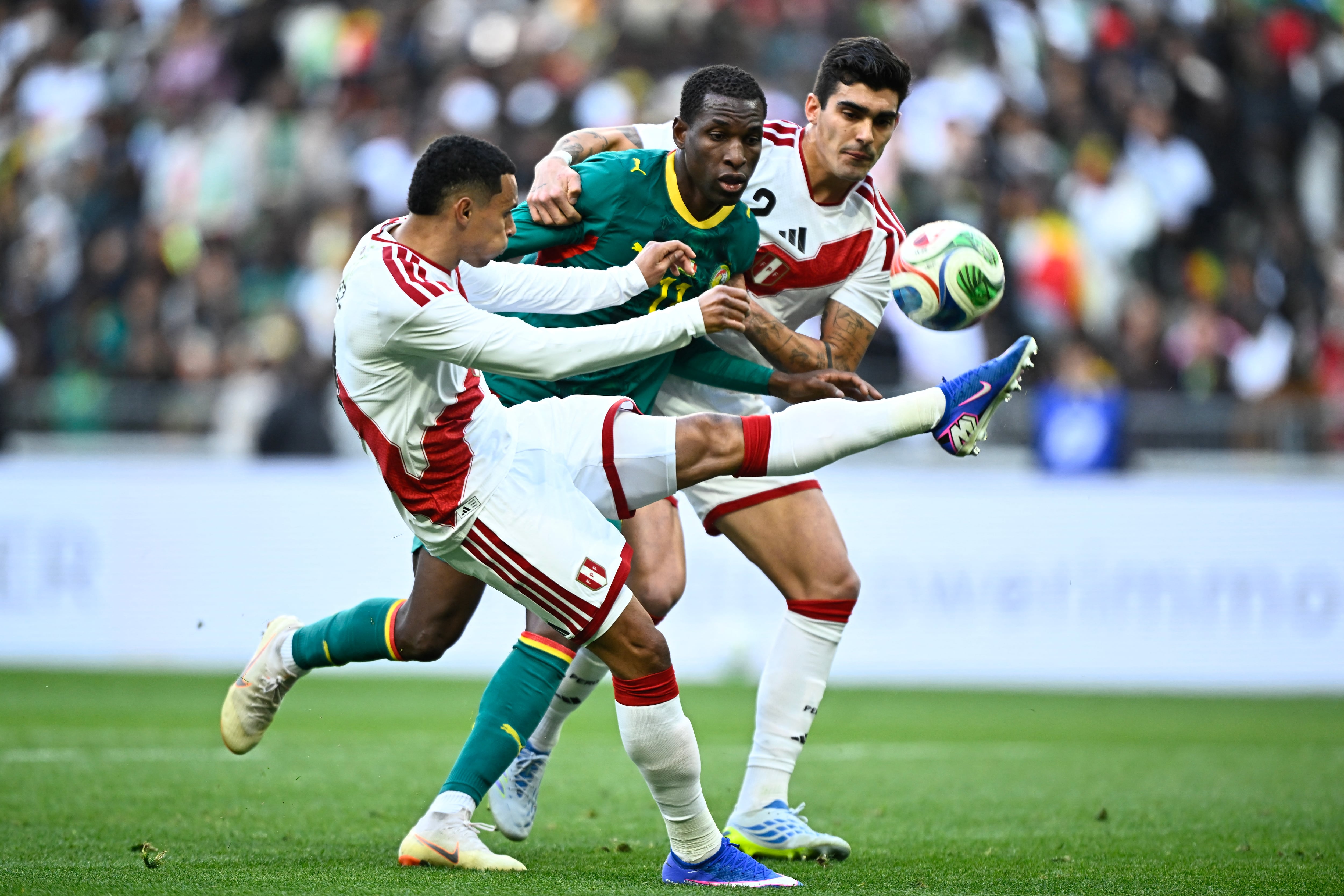 Senegal's forward #11 Nicolas Jackson (C) fights for the ball with Peru's defender #02 Alfonso Barco (R) during the international friendly football match between Senegal and Peru at the Stade de France in Saint-Denis, north of Paris, on March 28, 2026 (Photo by JULIEN DE ROSA / AFP)