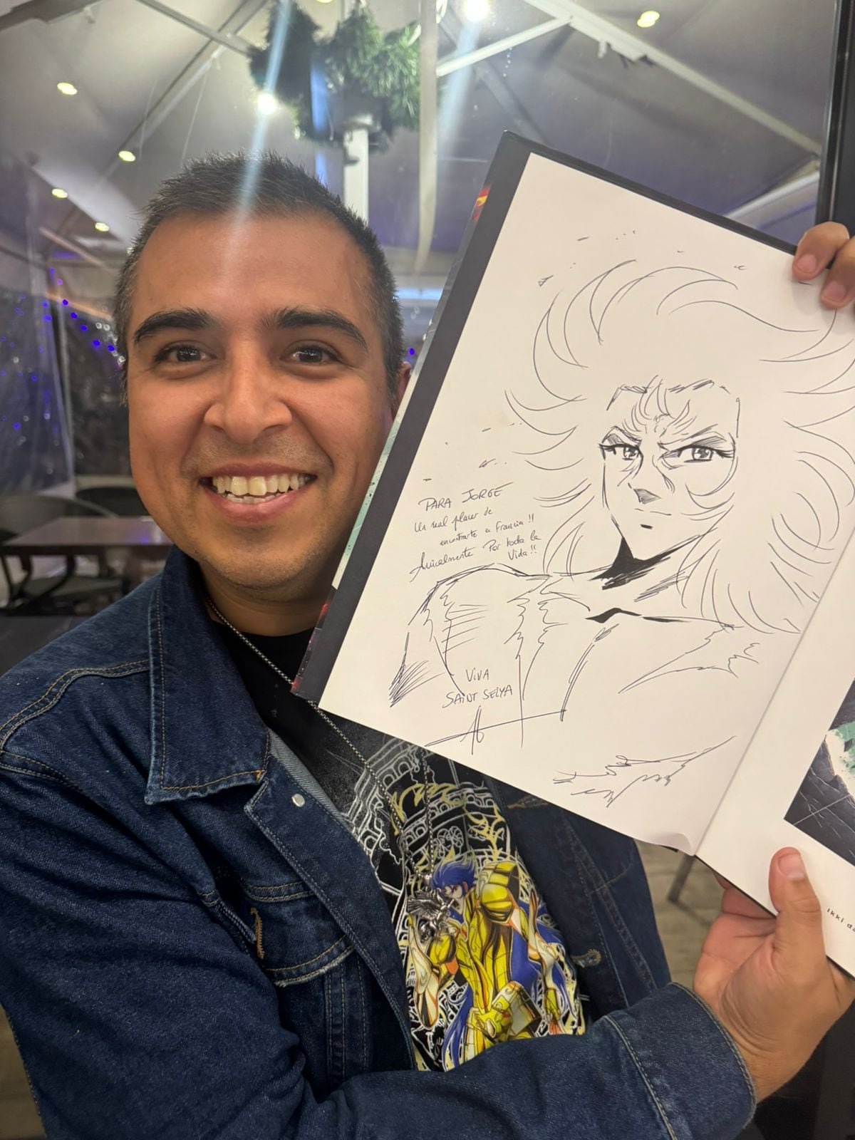 Jorge de Pegaso posa con el dibujo de Guilty (personaje peruano de Caballeros del Zodiaco) realizado por Jerome Alquie durante su reunión. (Foto: Jorge Vásquez)