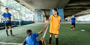 Niña ayuda a su compañero en pleno juego. Foto: Istock