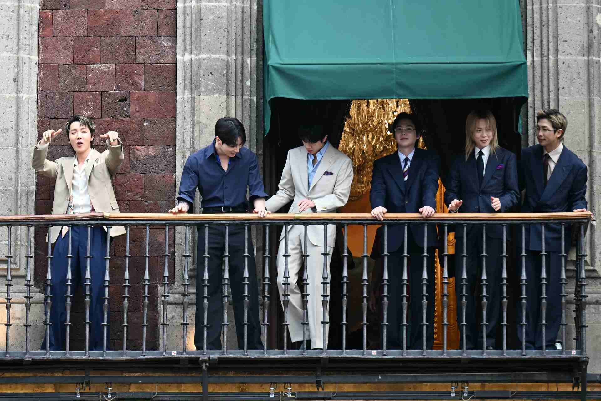 J-Hope (izquierda) y otros miembros del grupo surcoreano de K-pop BTS saludan a sus fans desde el balcón del Palacio Nacional, en la plaza del Zócalo de la Ciudad de México, el 6 de mayo de 2026. BTS ofrecerá tres conciertos con entradas agotadas en el Estadio GNP Seguros de la Ciudad de México los días 7, 9 y 10 de mayo. (Foto de YURI CORTEZ / AFP)