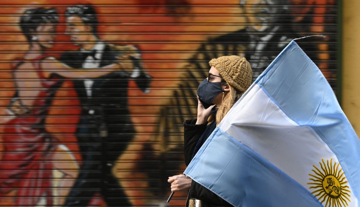 Una mujer sostiene una bandera argentina durante una protesta contra las políticas de salud del presidente de Argentina, Alberto Fernández. (JUAN MABROMATA / AFP).