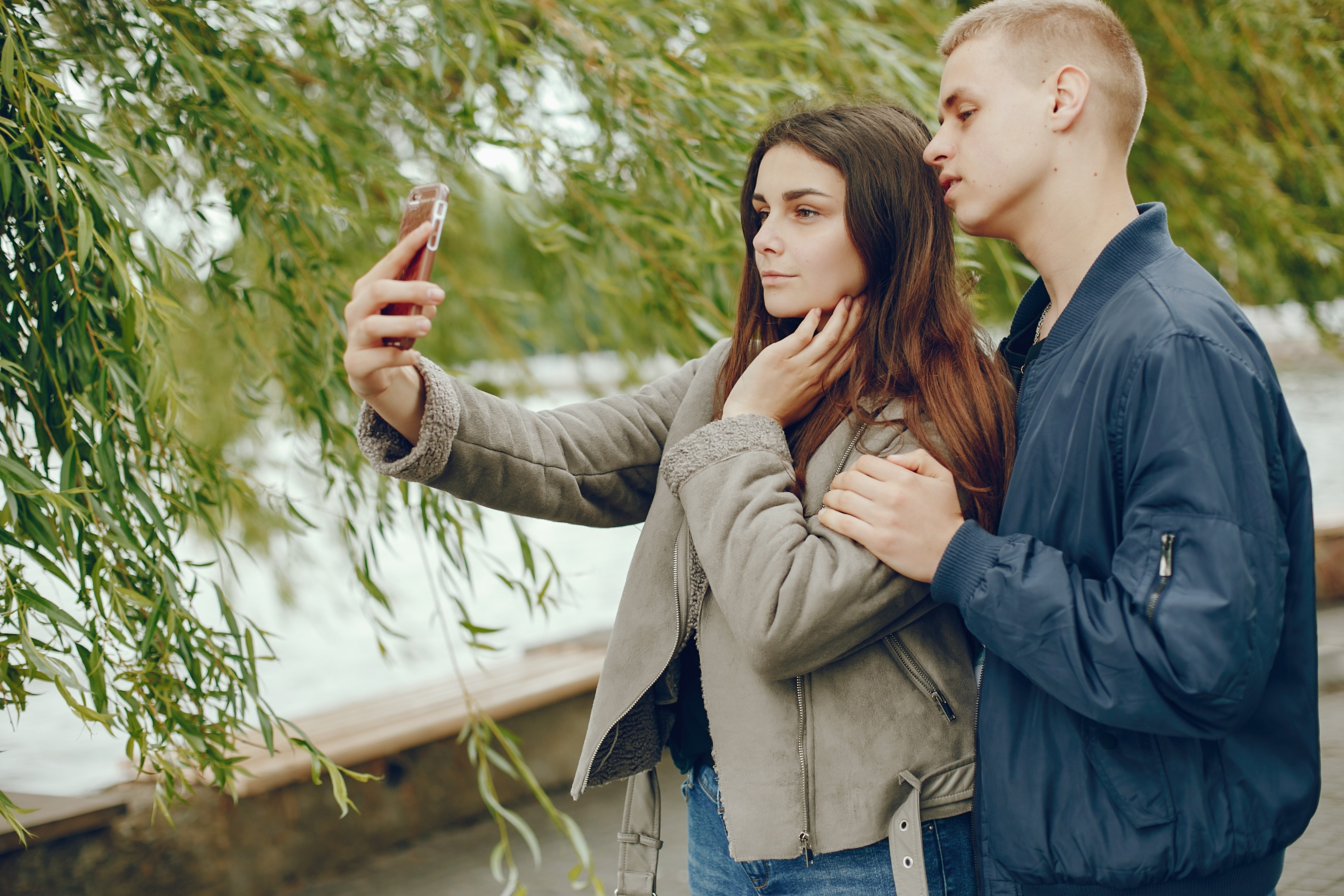 Lovely couple in a summer park. Boy with his girlfriend. Girl with smartphone