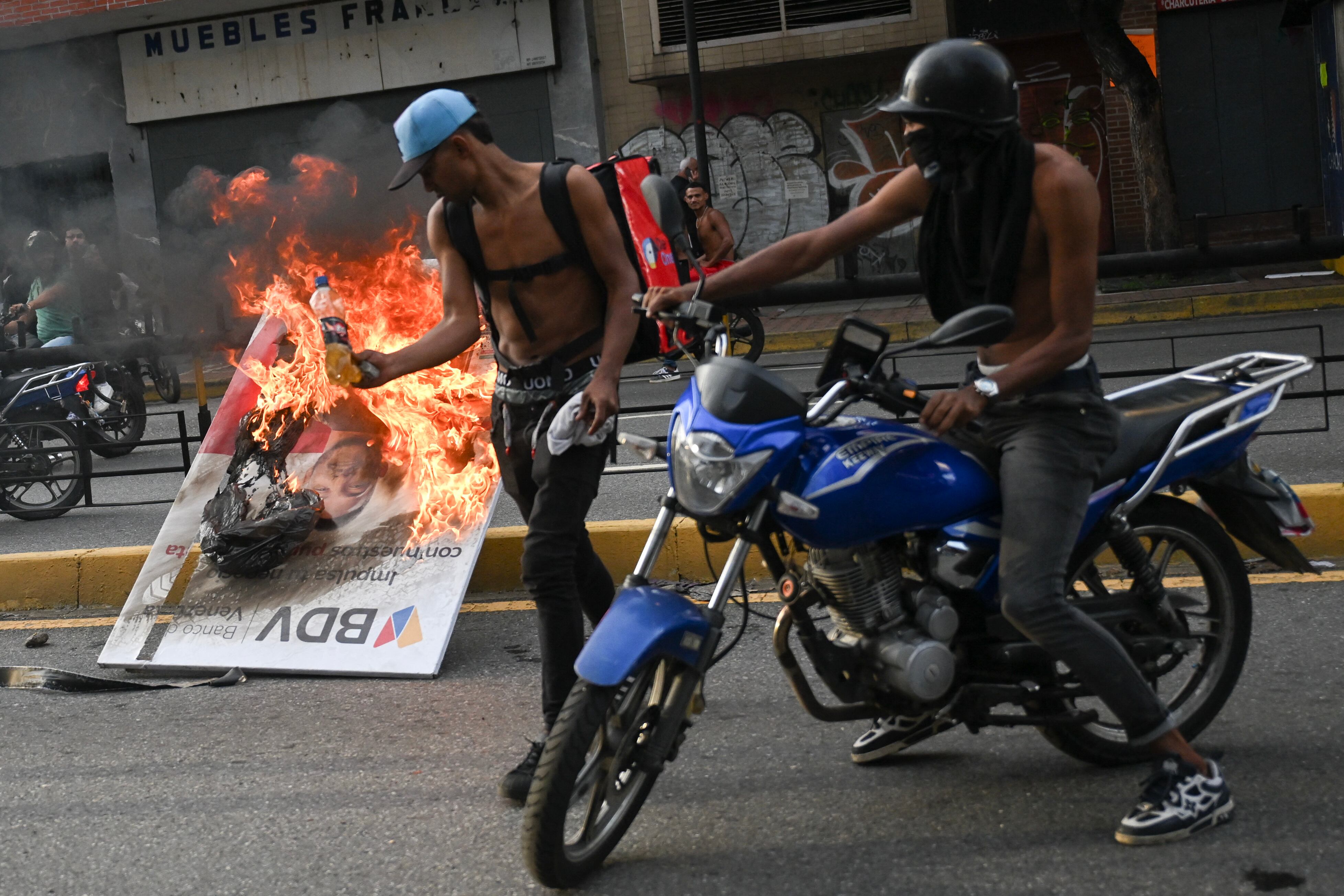 Los manifestantes queman una pancarta publicitaria durante una protesta contra el gobierno del presidente de Venezuela Nicolás Maduro en Caracas el 29 de julio de 2024. (Foto de Raúl ARBOLEDA / AFP).