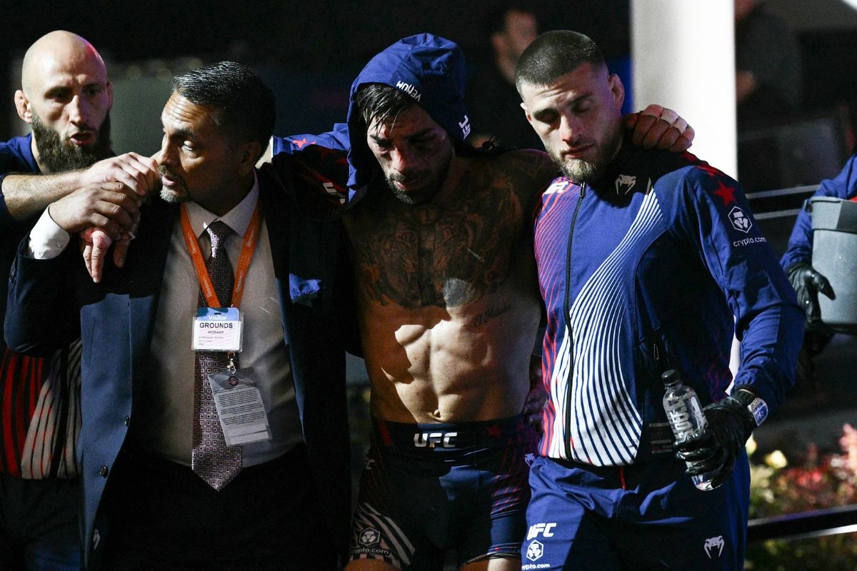 Ilia Topuria es auxiliado para salir de la jaula de acero. Sufrió la peor derrota de su carrera. (Fotos: Brendan SMIALOWSKI / AFP)