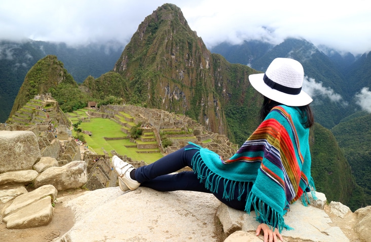 Young female traveler admiring the Inca ruins of Machu Picchu, one of the New Seven Wonder of The World, Cusco Region, Urubamba Province, Peru