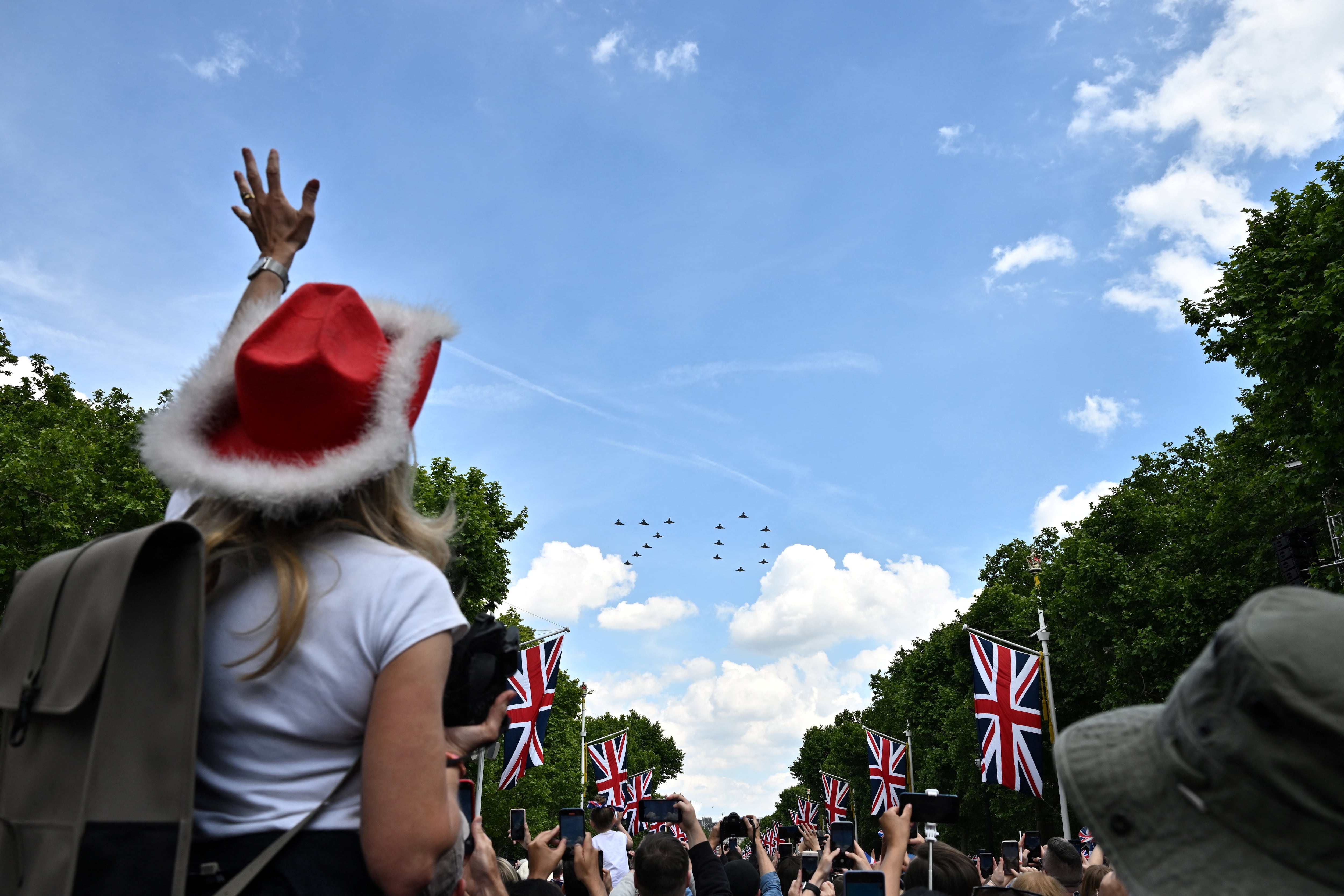 Los miembros del público aplauden mientras ven al equipo acrobático de la Royal Air Force, las Flechas Rojas, volar en formación para formar el número '70', durante el Desfile del Cumpleaños de la Reina, el Trooping the Colour, como parte de las celebraciones del Jubileo de Platino de la Reina Isabel II. (Foto de Ben Stansall / AFP)