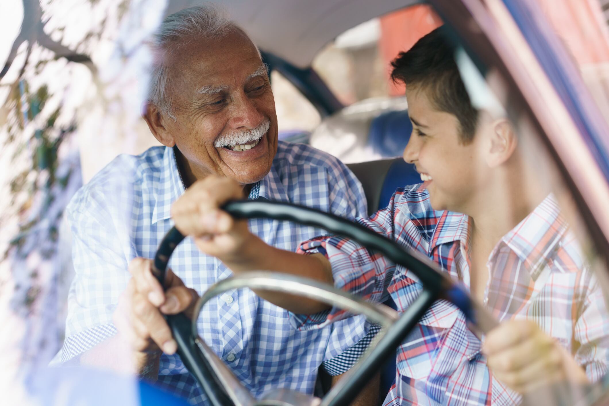 Adulto mayor en un auto junto a su nieto. Foto: Istock