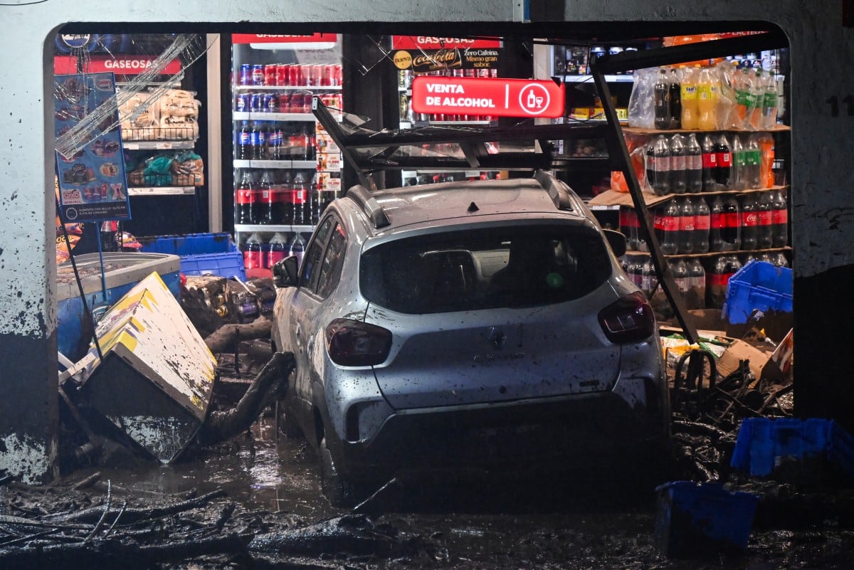 Un vehículo permanece entre barro y escombros dentro de un local dañado por un alud de barro en la comuna de Las Condes, Santiago, el 8 de octubre de 2026. (RODRIGO ARANGUA / AFP)