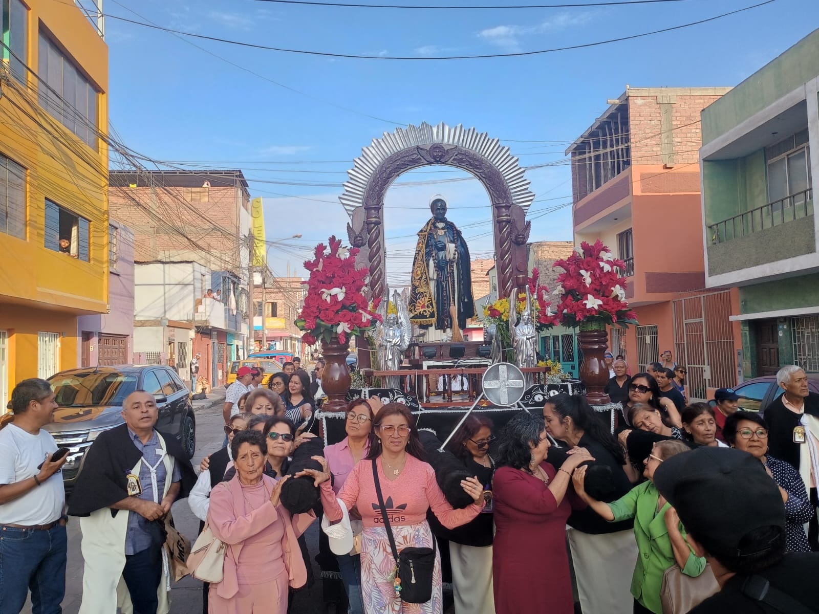 Fieles llevan las andas de San Martín de Porres en procesión.