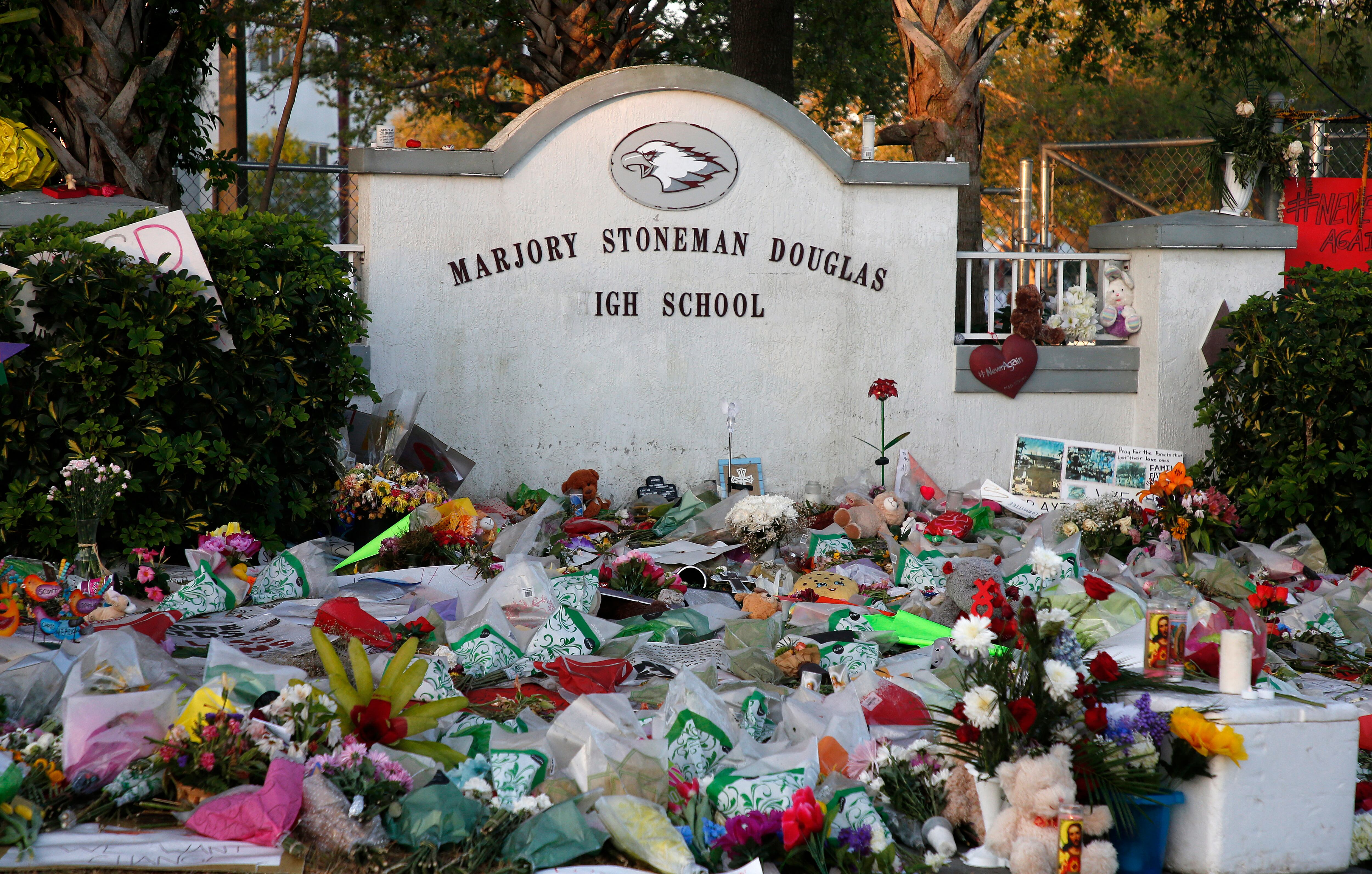 Flores, velas y recuerdos se sientan fuera de uno de los monumentos conmemorativos improvisados en la escuela secundaria Marjory Stoneman Douglas en Parkland, Florida, el 27 de febrero de 2018. (Foto de RHONA WISE / AFP)