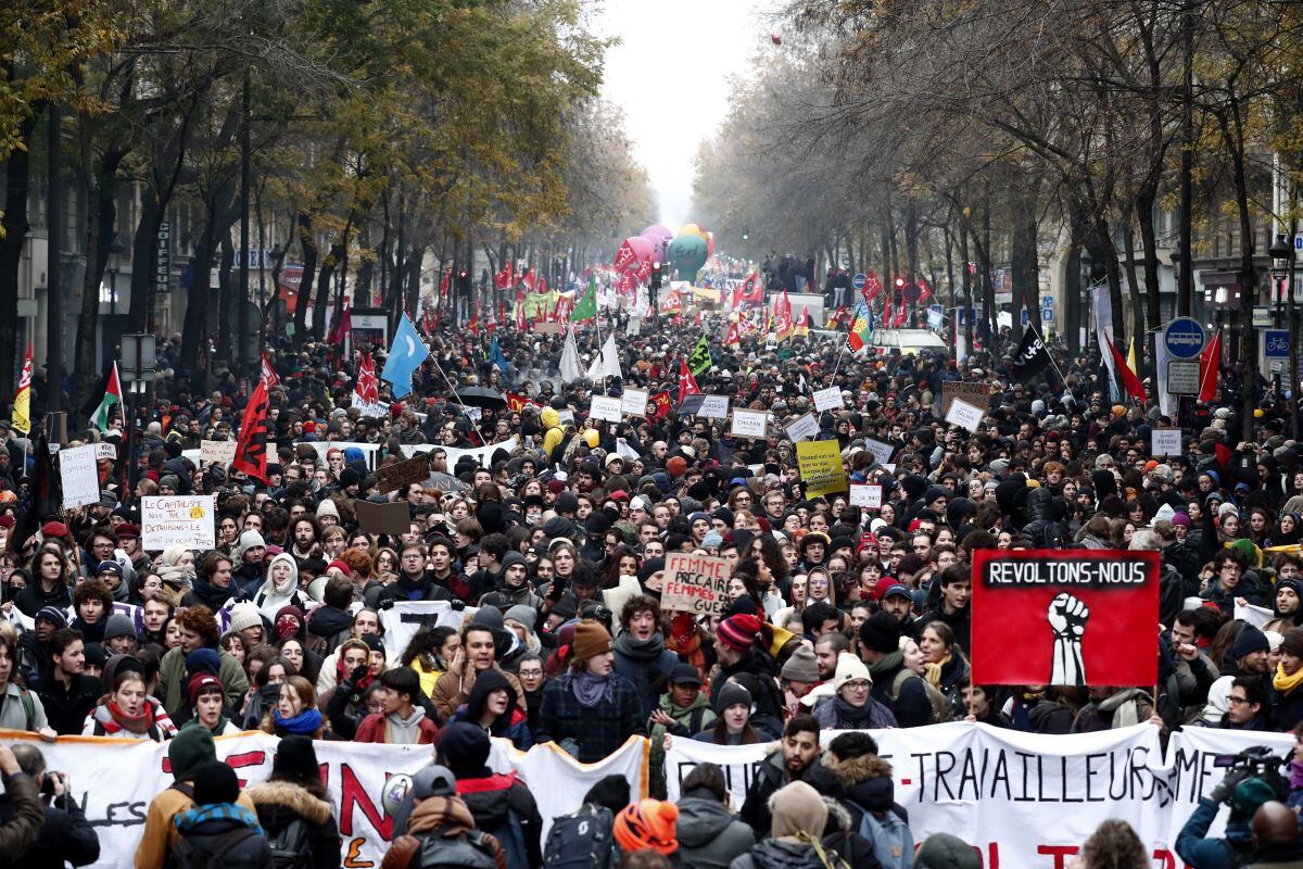 Los manifestantes sujetan una pancarta en la que se puede leer "revoltons-nous",(lit. vamos a rebelarnos), durante una protesta contra la reforma de las pensiones, madre de todas las reformas del presidente francés, Emmanuel Macron, este jueves en París. Las pensiones se someten desde ayer a la prueba de la calle con una huelga que, en los transportes y otros sectores que ven amenazados sus regímenes especiales, puede convertirse en indefinida y paralizar el país. (EFE)