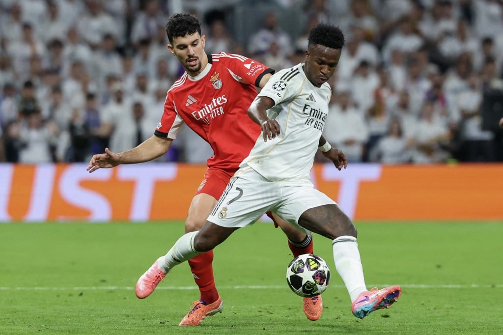 Real Madrid's Brazilian forward #07 Vinicius Junior (R) is challenged by SL Benfica's Portuguese defender #44 Tomas Araujo during the UEFA Champions League knockout round play-off second leg football match between Real Madrid CF and SL Benfica at Santiago Bernabeu Stadium in Madrid on February 25, 2026. (Photo by Pierre-Philippe MARCOU / AFP)
