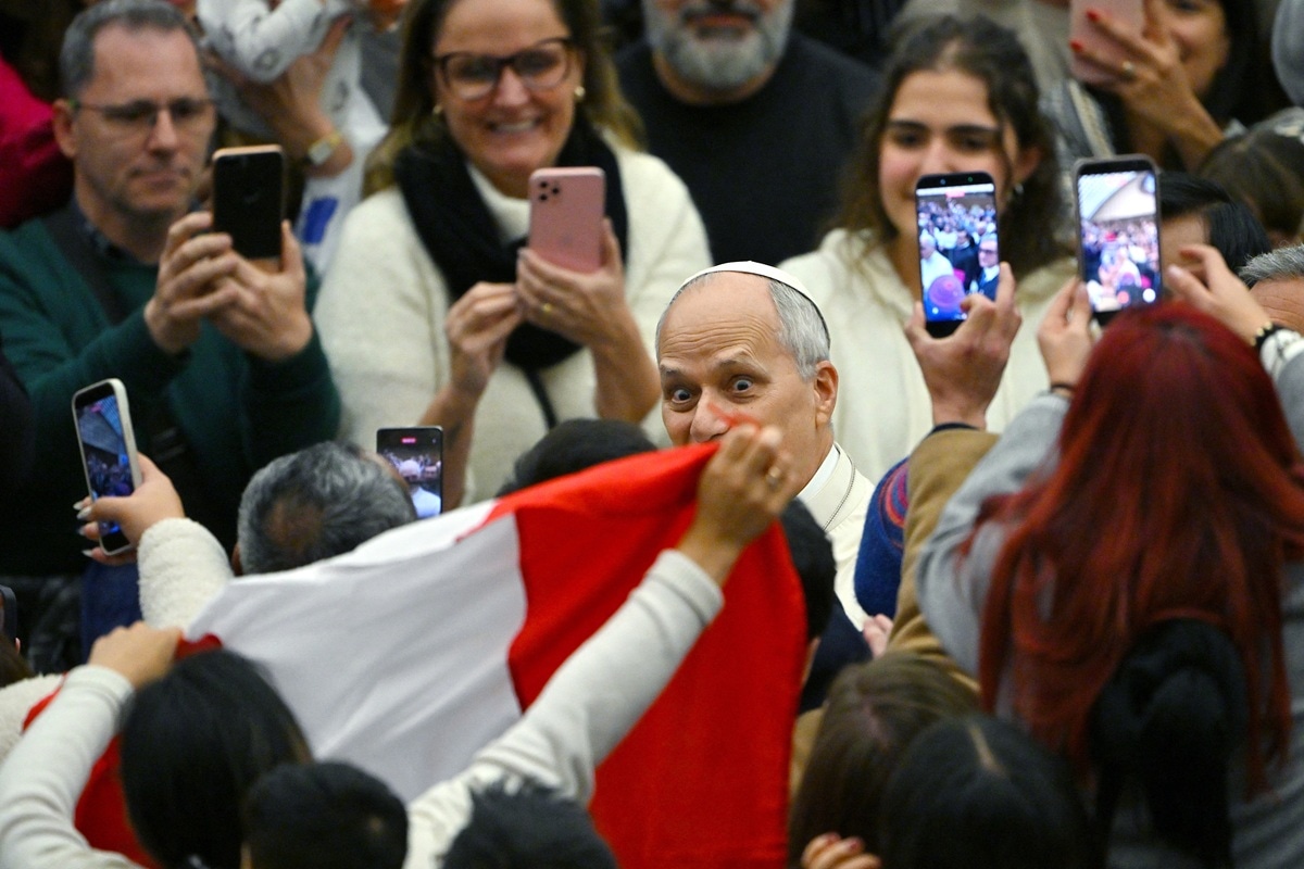 El papa León XIV reacciona ante los fieles que lo aclaman con una bandera peruana cuando sale de su audiencia general semanal en el Aula Pablo VI del Vaticano, el 14 de enero de 2026. (Andreas SOLARO / AFP)