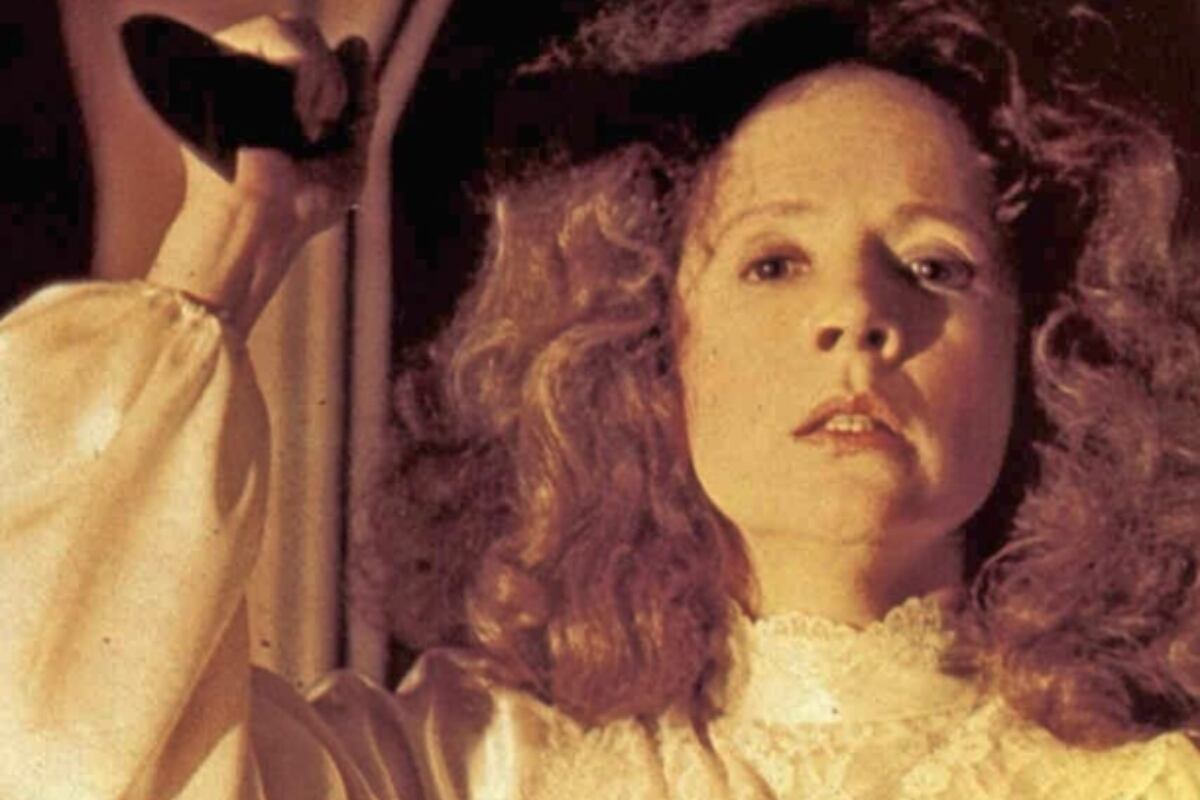 Margarite White (Piper Laurie) con una bata blanca y alzando un cuchillo (Foto: Two Pines entertainment)