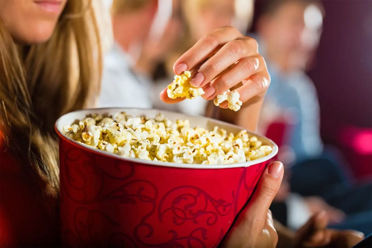 Una joven y una bandeja llena de pop corn o palomita de maíz (Foto: ShutterStock)