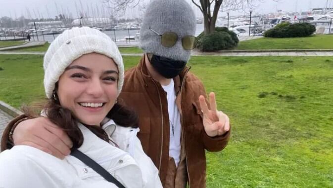 Los actores Alp Navruz y Ayça Ayşin muy contentos caminando por un parque.