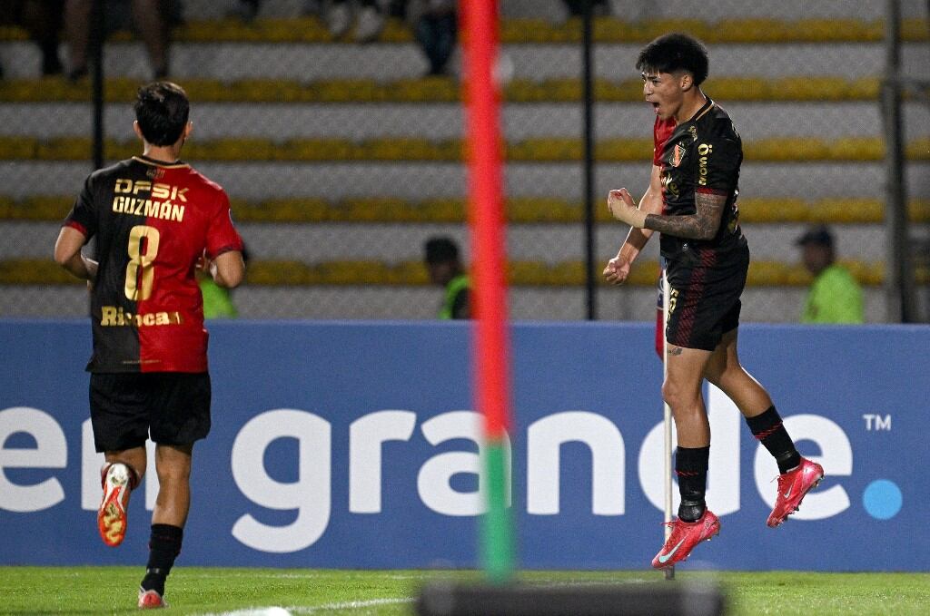 Melgar's midfielder #26 Kenji Cabrera (R) celebrates past teammate Argentine forward #08 Brian Guzman after scoring a penalty goal during the Copa Sudamericana group stage football match between Venezuela's Academia Puerto Cabello and Peru's Melgar at the Polideportivo Misael Delgado stadium in Valencia, state of Carabobo, Venezuela, on May 13, 2025. (Photo by Federico PARRA / AFP)