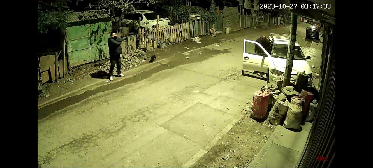 Uno de los rateros ya logró abrir la puerta del carro mientras que otro observa a la casa.