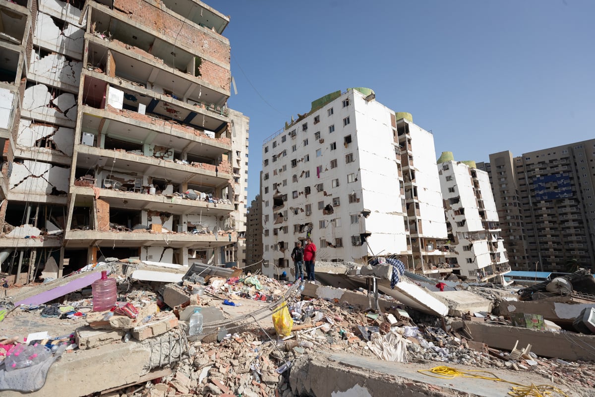 Personas caminan entre escombros de edificios afectados por terremotos, en Catia La Mar, Venezuela, el 25 de junio de 2026. (Ronald Peña R / EFE)