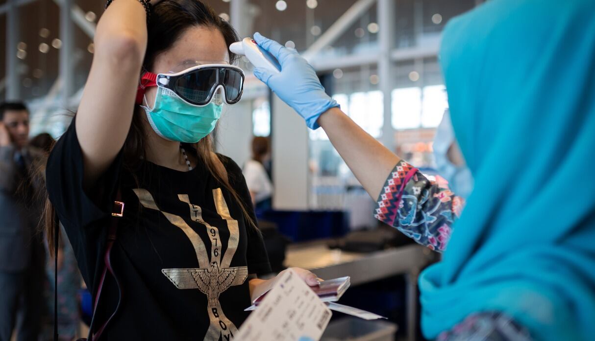 Imagen referencial. Una azafata de Malaysia Airlines verifica la temperatura de un pasajero en medio de la pandemia del coronavirus. Fotografía del 14 de febrero de 2020. (NICOLAS ASFOURI / AFP).
