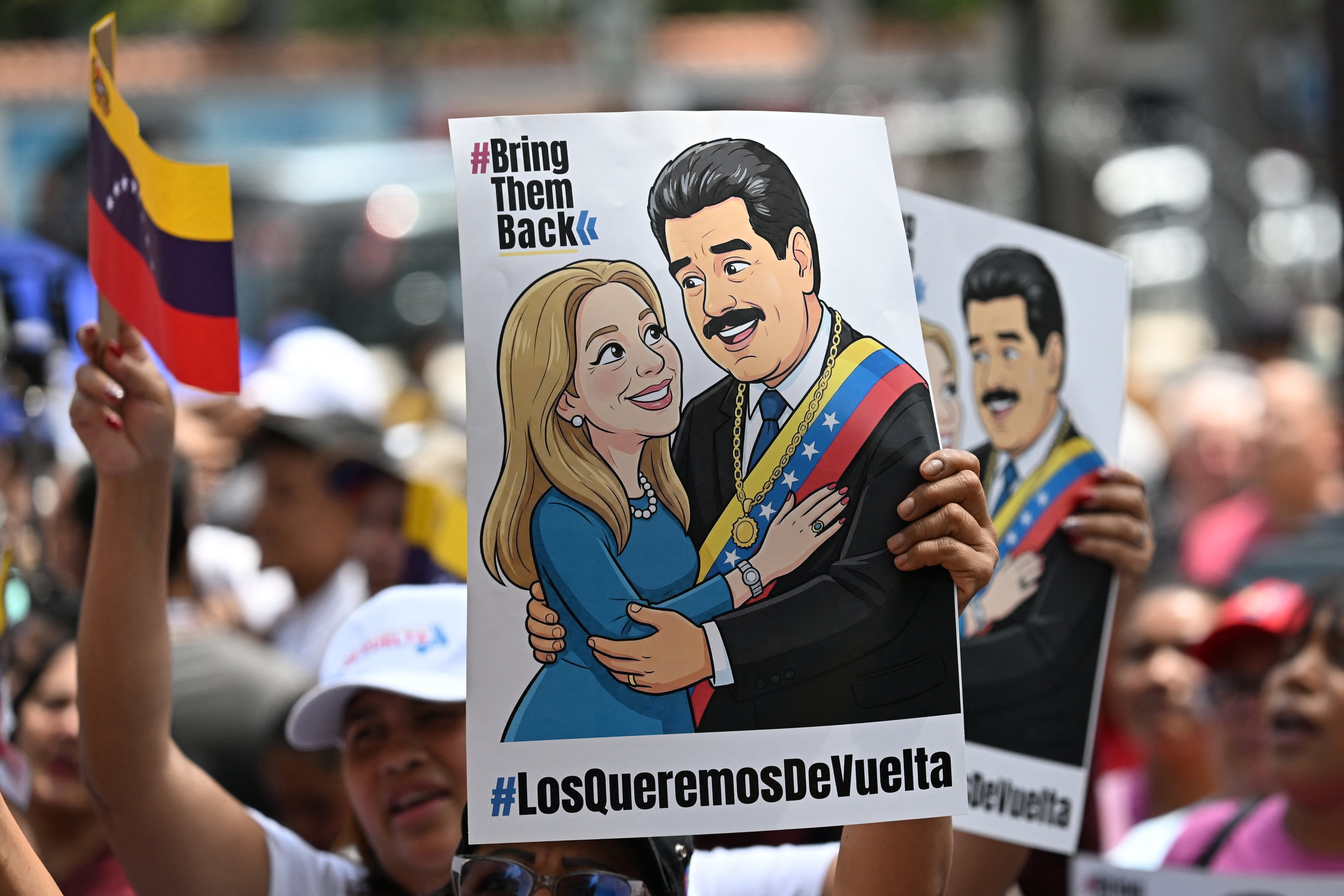 Partidarios del derrocado mandatario de Venezuela Nicolás Maduro se manifiestan con un cartel de él y su esposa Cilia Flores con el lema "Los queremos de vuelta", en Caracas el 26 de marzo de 2026. (Foto de Juan BARRETO / AFP).