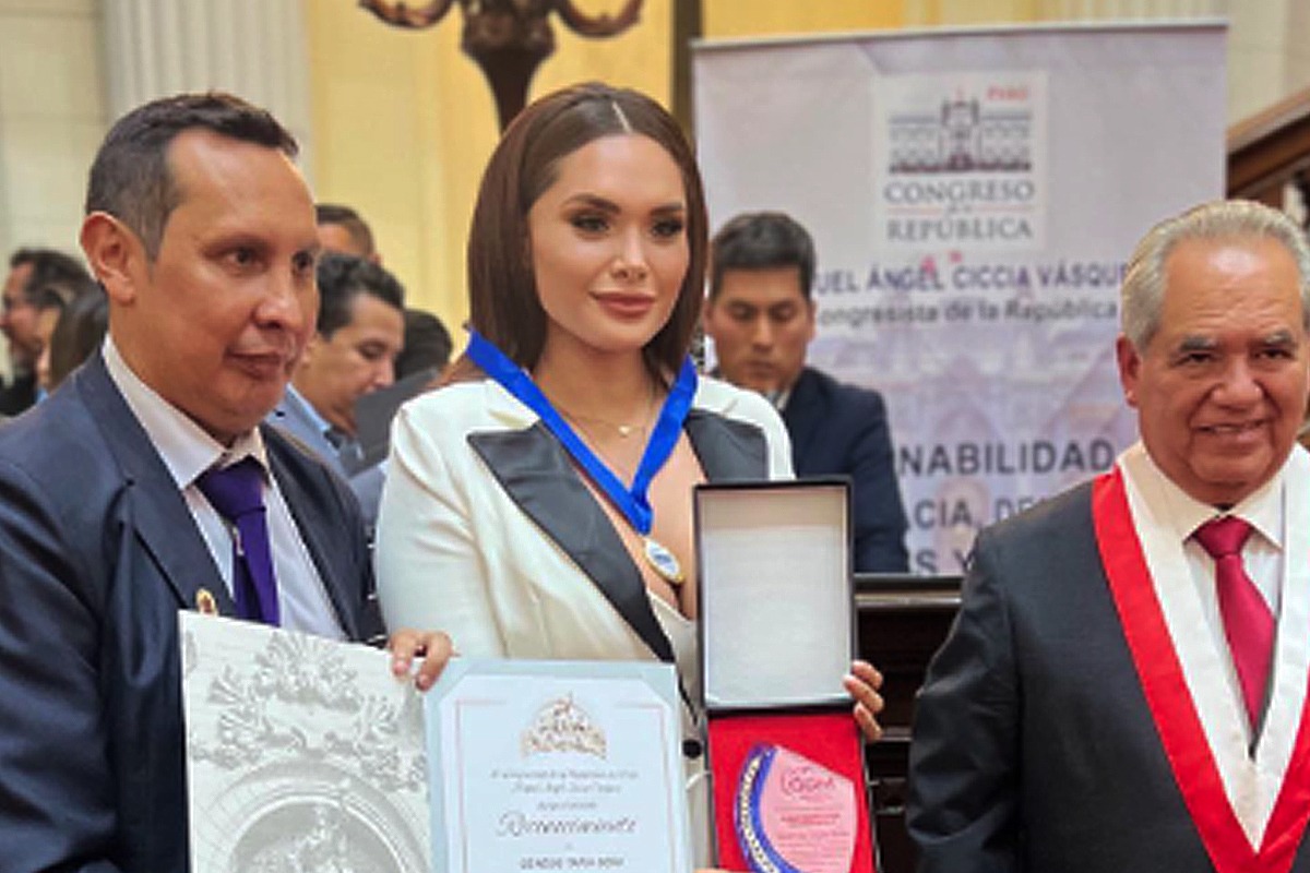 Génesis Tapia con su condecoración y al lado derecho el congresista Miguel Ángel Ciccia.