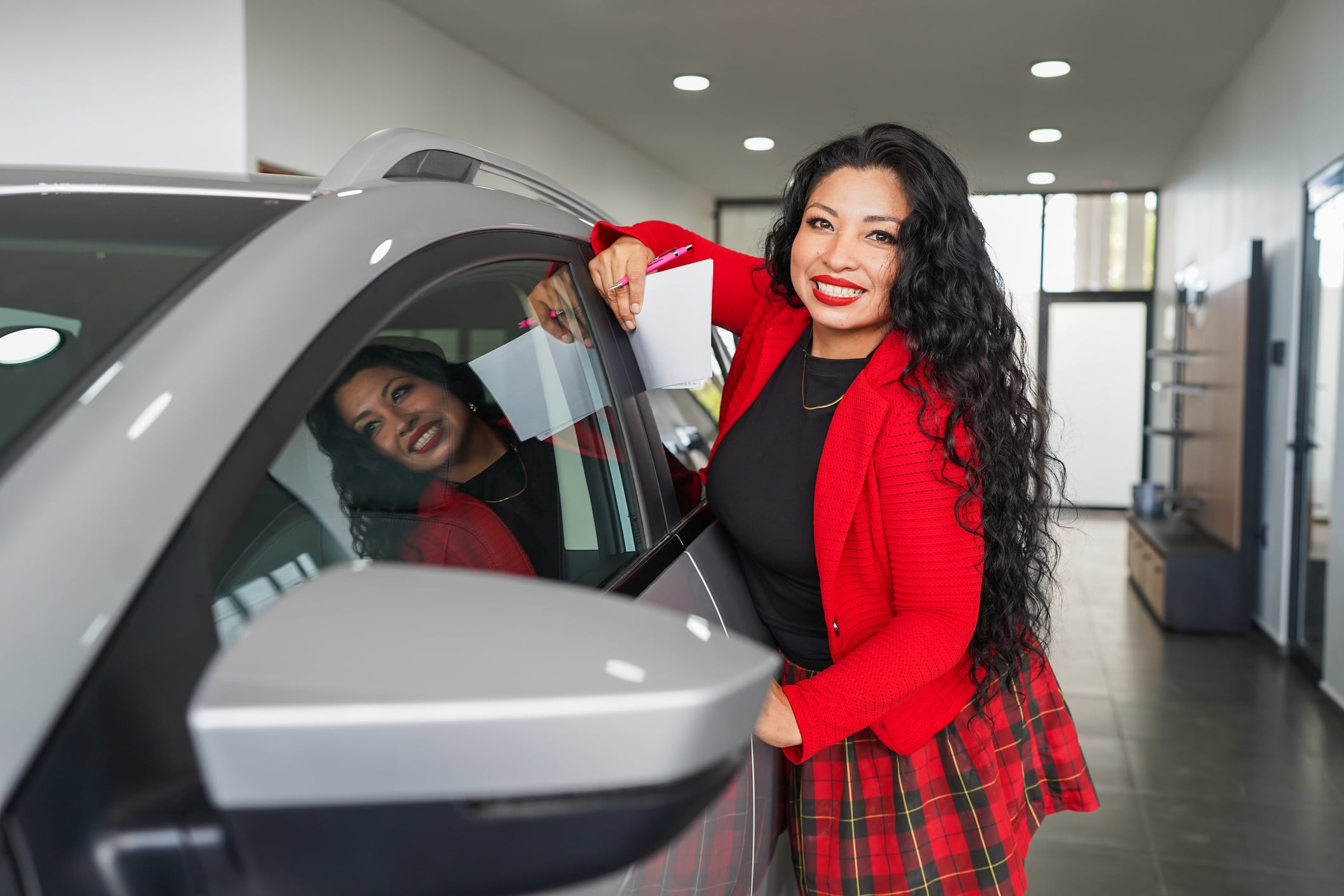Mujer muestra orgullosa uno de sus bienes, un auto. Foto: Istock