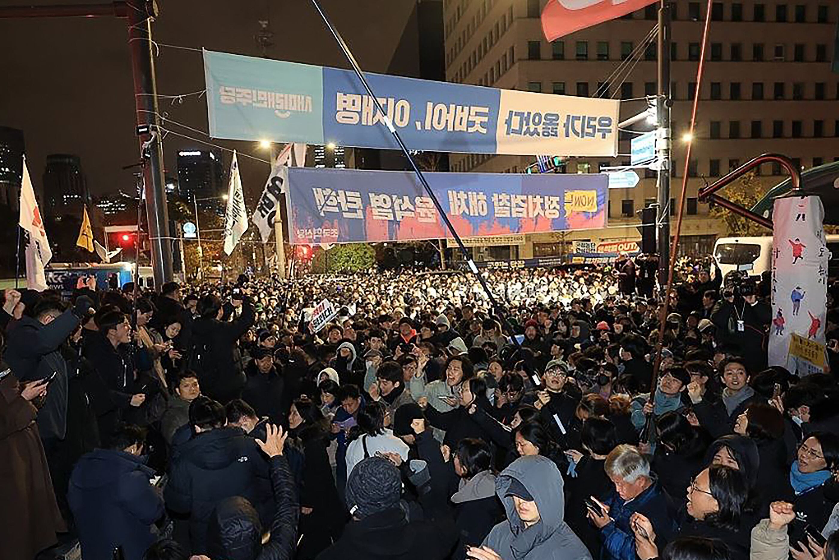 La gente se reúne frente a la Asamblea Nacional en Seúl el 4 de diciembre de 2024, después de que el presidente de Corea del Sur, Yoon Suk Yeol, declarara la ley marcial de emergencia. (Foto de YONHAP / AFP)