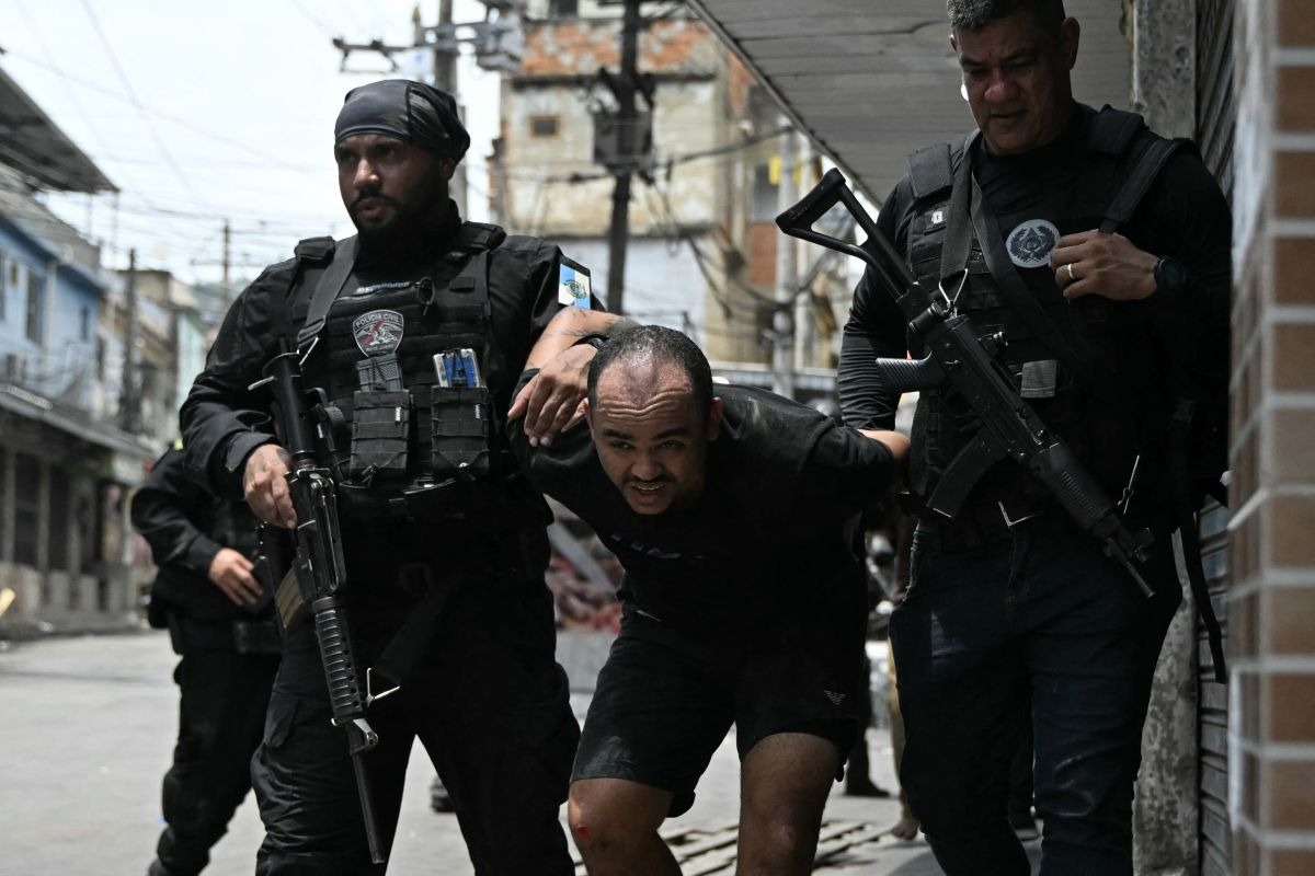 Un sospechoso es escoltado por agentes de policía tras ser detenido en la favela Vila Cruzeiro. (Foto: Mauro PIMENTEL / AFP)