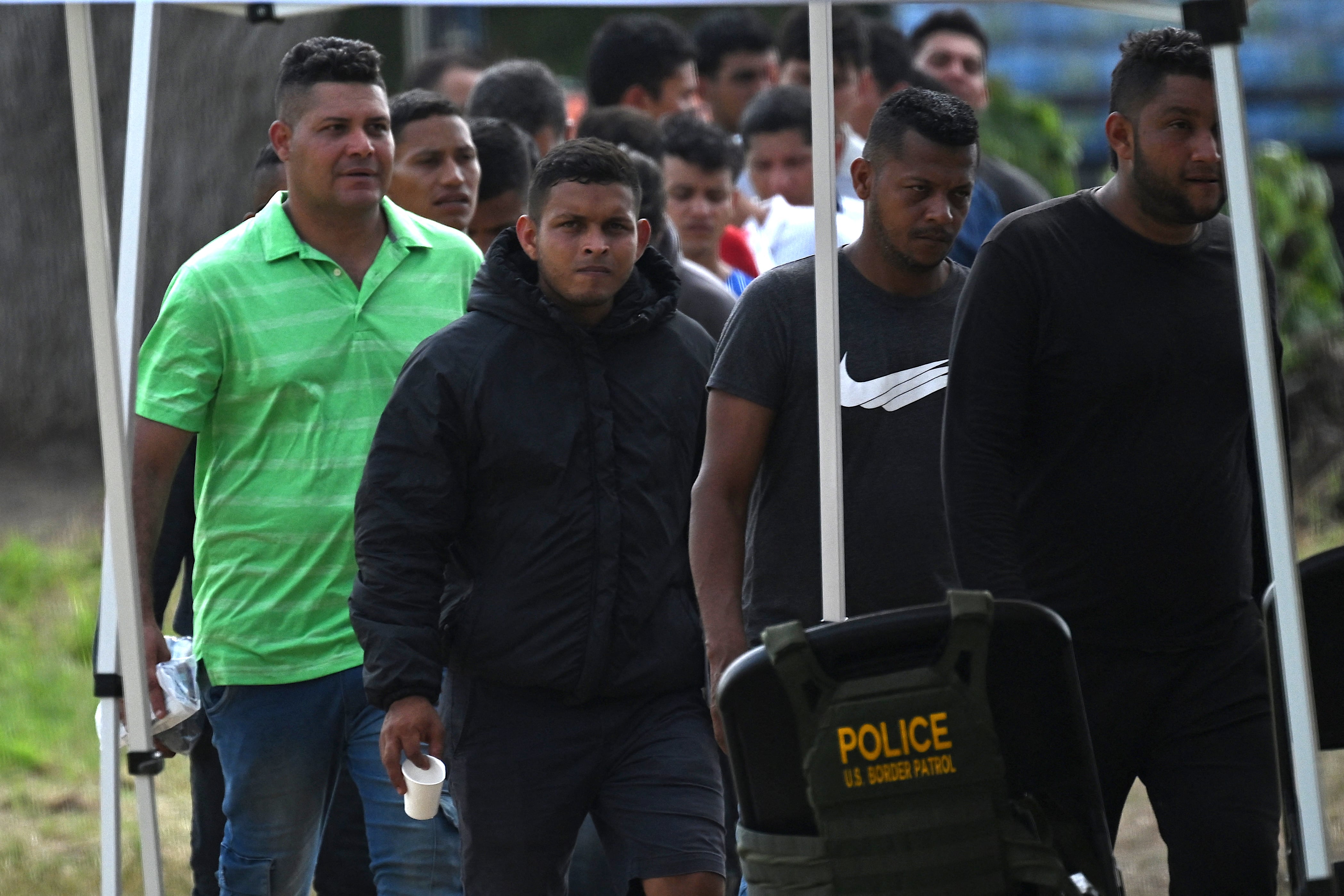 Migrantes hacen fila mientras esperan ser procesados por la Patrulla Fronteriza de Estados Unidos después de cruzar a Brownsville, Texas. (Foto de ANDREW CABALLERO-REYNOLDS / AFP).