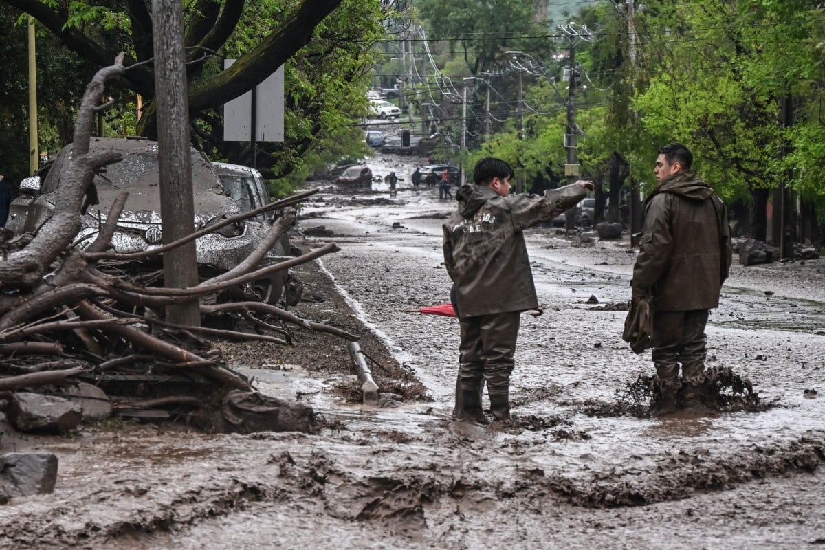 Agentes de Carabineros permanecen en una calle cubierta de barro tras un deslizamiento de tierra en la comuna de Las Condes, Santiago, el 8 de octubre de 2026. (RODRIGO ARANGUA / AFP)