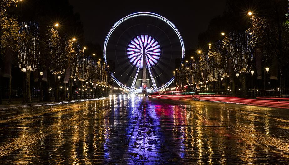 Luces de navidad cuelgan de árboles durante una noche lluviosa en la avenida de los Campos Elíseos, en París (Francia). (EFE)