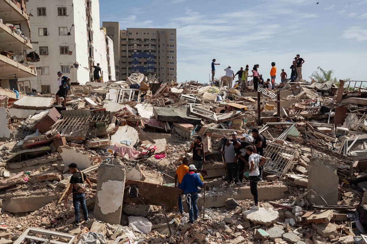 Personas caminan entre escombros de edificios afectado por terremotos, en Catia La Mar, Venezuela, el 25 de junio de 2026. (Ronald Peña R. / EFE)