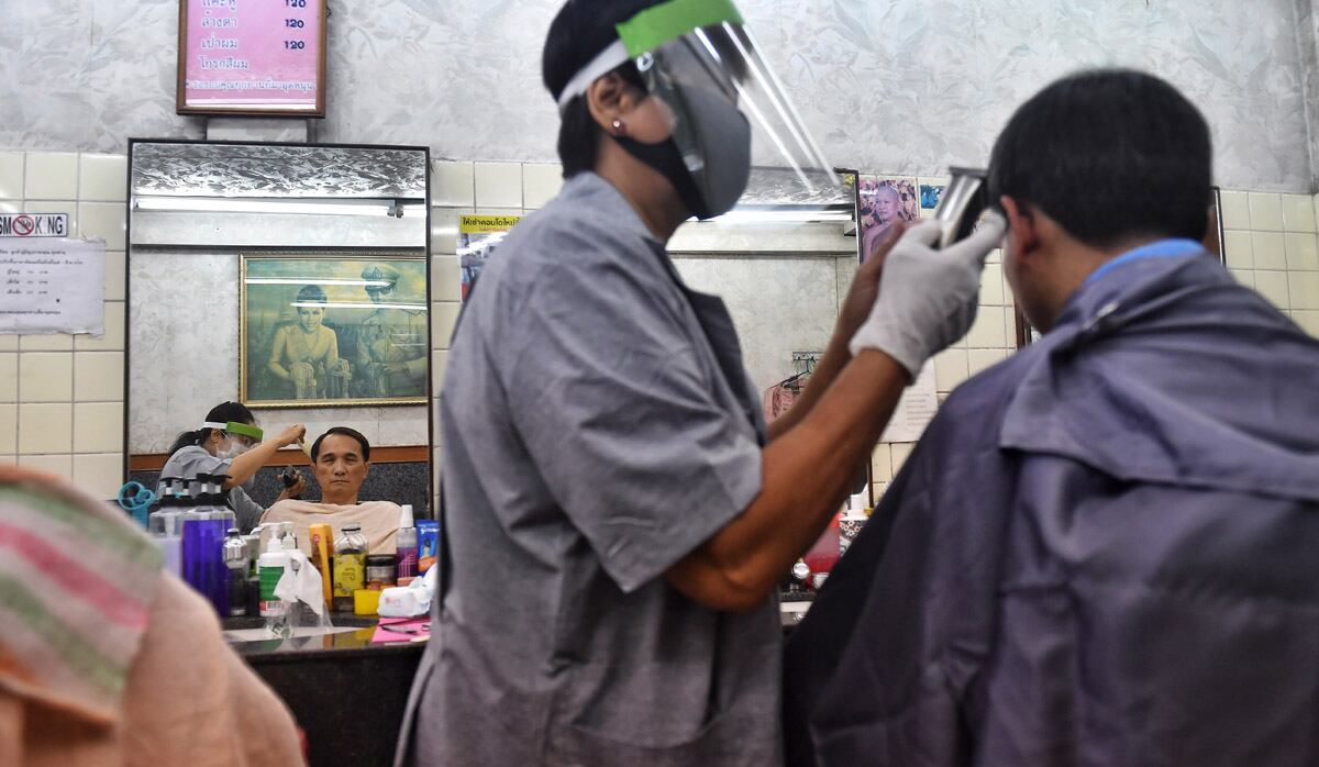 Los peluqueros usan máscaras y máscaras faciales, en Bangkok, después de que se reabrieron algunos negocios debido a una disminución de las medidas para combatir la propagación del nuevo coronavirus COVID-19, en Tailandia. (Foto: AFP/Lillian SUWANRUMPHA)