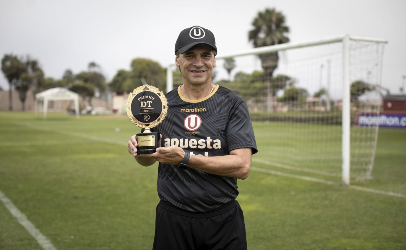 El técnico Fabián Bustos posa junto al trofeo a "mejor equipo masculino 2024" que ganó Universitario de Deportes en las votaciones de los Premios DT El Comercio 2024. (Foto: Joel Alonzo / El Comercio)