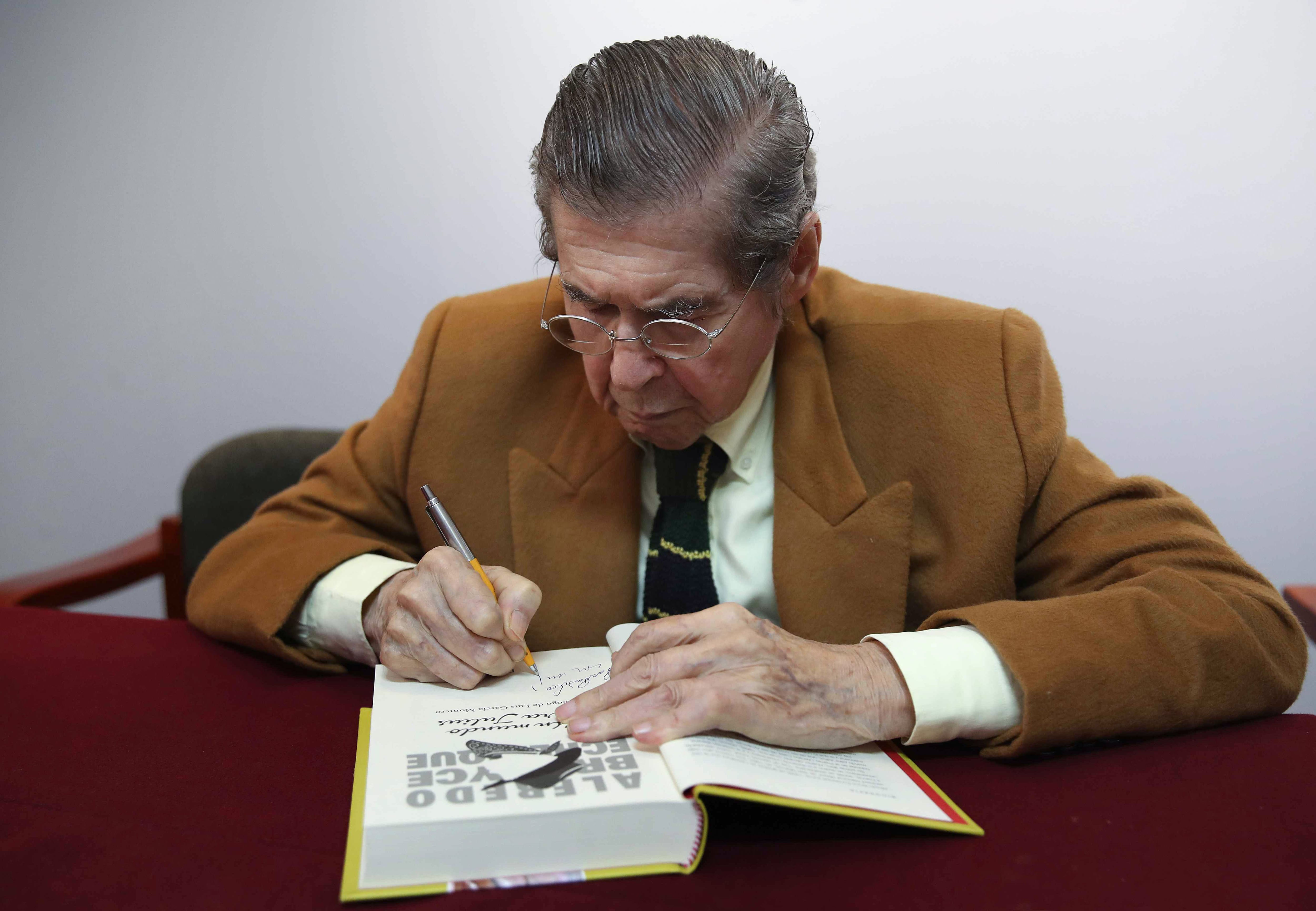 Alfredo Bryce Echenique (1939) firma el manuscrito original de su obra 'Un mundo para Julius' durante acto en el Instituto Cervantes. | Foto: EFE