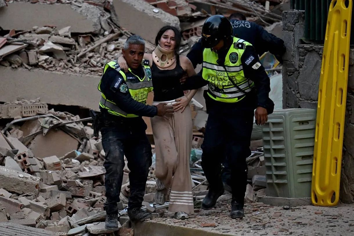 Agentes de la policía municipal evacúan a una persona herida de un edificio derrumbado tras un terremoto en Caracas. Foto: AFP