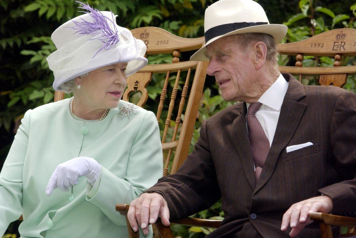 En esta foto de archivo tomada el 17 de julio de 2002, la reina Isabel II (izquierda) y el príncipe Felipe (derecha) conversan sentados durante una actuación musical en Inglaterra. (Fiona HANSON / POOL / AFP).