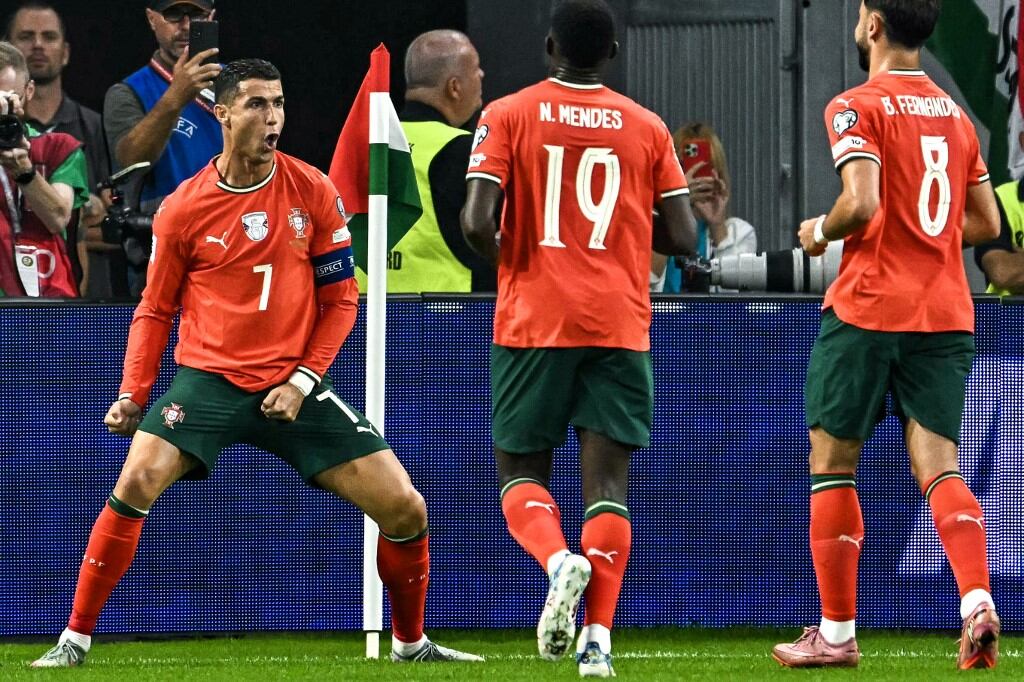 Portugal's forward #07 Cristiano Ronaldo (L) celebrates with team mates after scoring the 1-2 penalty goal during the 2026 World Cup qualifiers Europe zone group F football match between Hungary and Portugal on September 9, 2025 in Budapest, Hungary. (Photo by Attila KISBENEDEK / AFP)