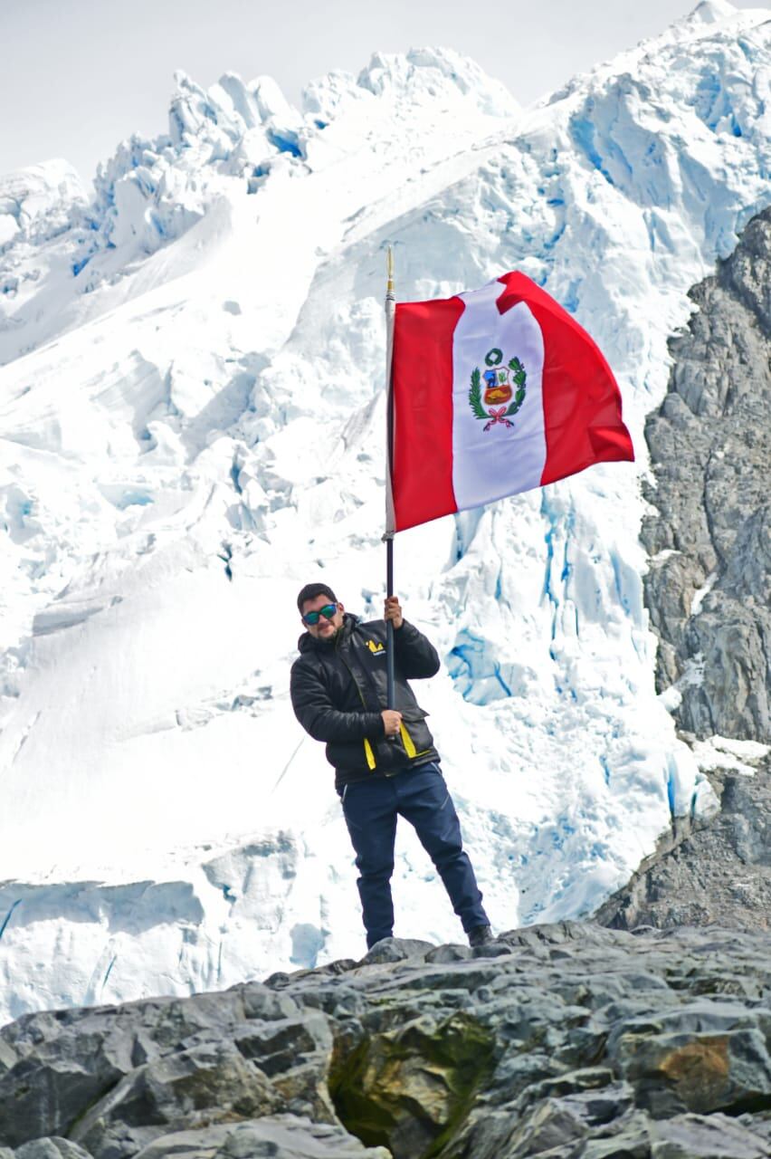 El reportero flameando la bandera peruana en la Antártida (Foto: Richard Rubiños, Marina de Guerra del Perú)