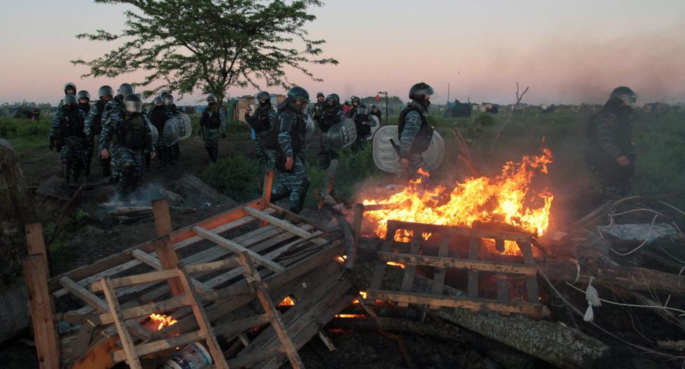La policía antidisturbios pasa junto a un incendio provocado por ocupantes ilegales durante un desalojo de tierras en Guernica, provincia de Buenos Aires, Argentina, el 29 de octubre de 2020. (AFP).
