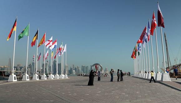 Una fotografía tomada el 14 de octubre de 2022 muestra a personas posando para una foto bajo el reloj de cuenta regresiva de la Copa Mundial en la capital de Qatar, Doha, antes de la Copa Mundial de Fútbol FIFA 2022. (Foto de Iván PISARENKO / AFP)