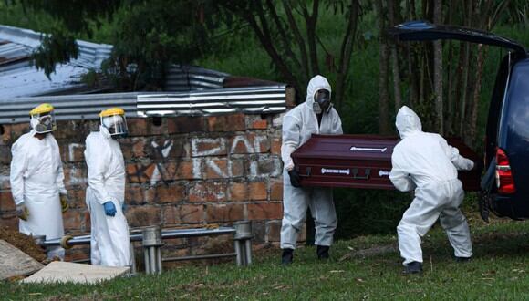 Trabajadores del cementerio entierran el ataúd de una mujer que supuestamente murió de COVID-19 en un cementerio en Medellín, Colombia. (AFP/JOAQUIN SARMIENTO).