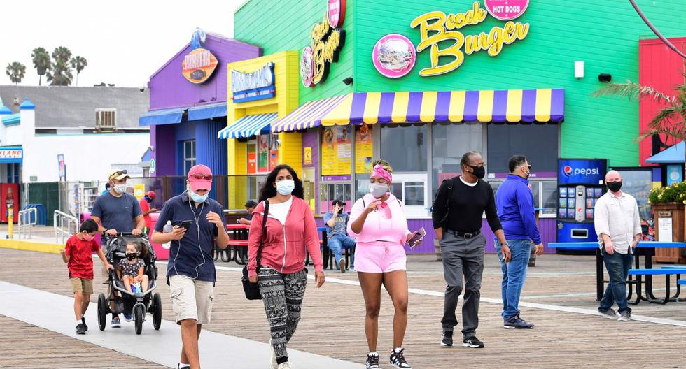 Las personas que usan máscaras faciales visitan el muelle de Santa Mónica, que volvió a abrir el 25 de junio después del cierre durante más de tres meses debido a la pandemia de coronavirus. (AFP / Frederic J. BROWN)