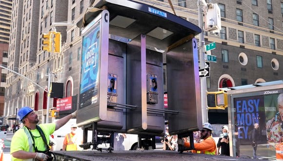 Trabajadores retiran el último teléfono público de la ciudad de Nueva York cerca de Seventh Avenue y 49th Street en Midtown Manhattan, ciudad de Nueva York, el 23 de mayo de 2022. (Foto de TIMOTEO A. CLARY / AFP)