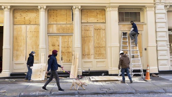 Los trabajadores colocan madera contrachapada sobre las ventanas de las tiendas como precaución contra posibles daños por protestas relacionadas con las elecciones en el barrio de SoHo en Nueva York. (EFE/JUSTIN LANE).